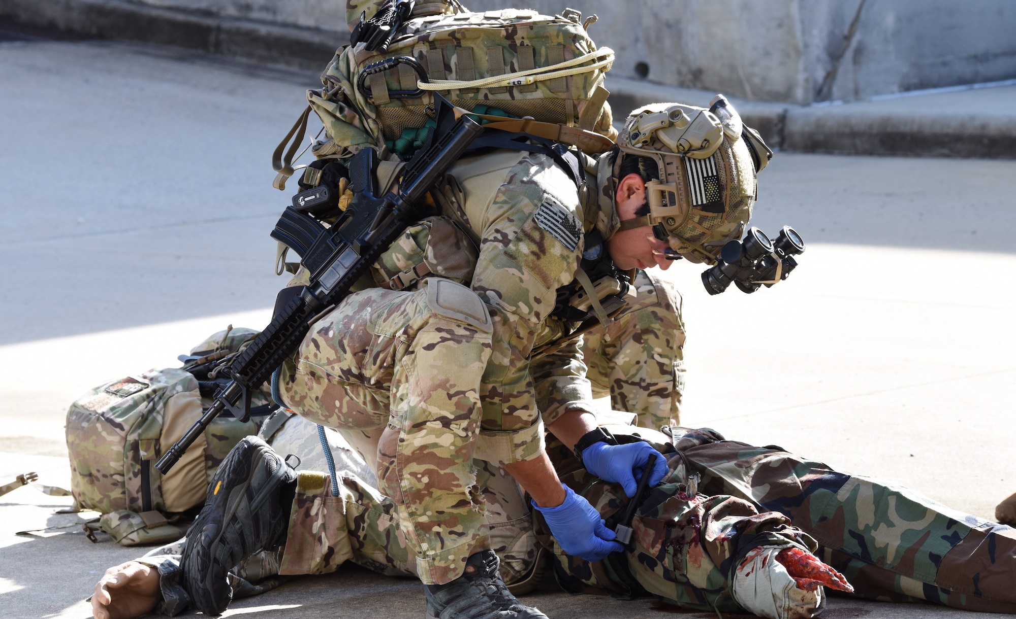 A U.S. Air Force Pararescuemen applies a tourniquet to a wounded mannequin.