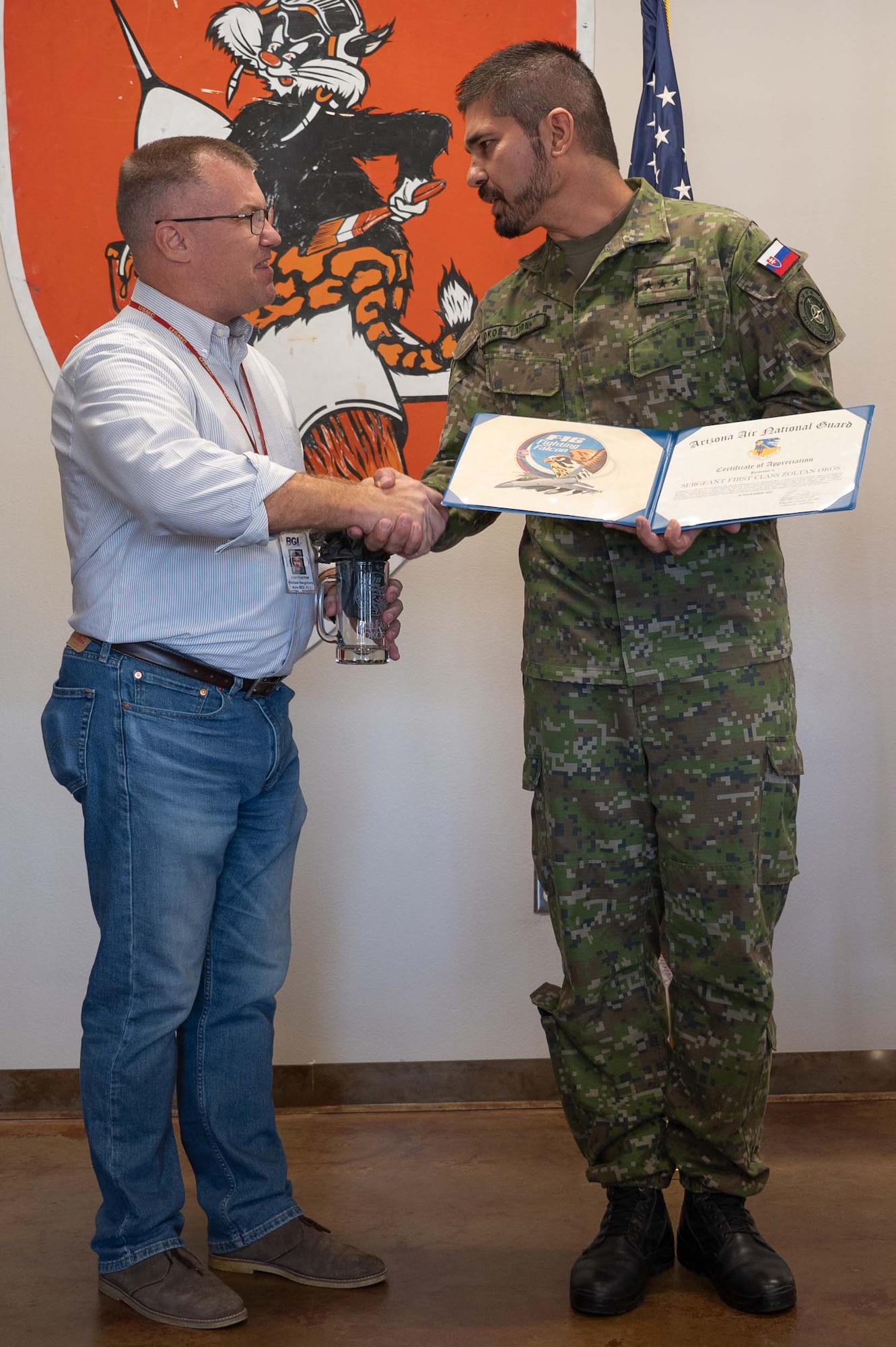 Mr. Michael Neighbors, 162nd Wing International Affairs, presents Slovak Liaison Officer assistant, Sergeant First Class Zoltan Okos, with a certificate of appreciation for his three years of service at Morris Air National Guard Base during a ceremony here today. (U.S. Air National Guard photo by Maj. Angela Walz)