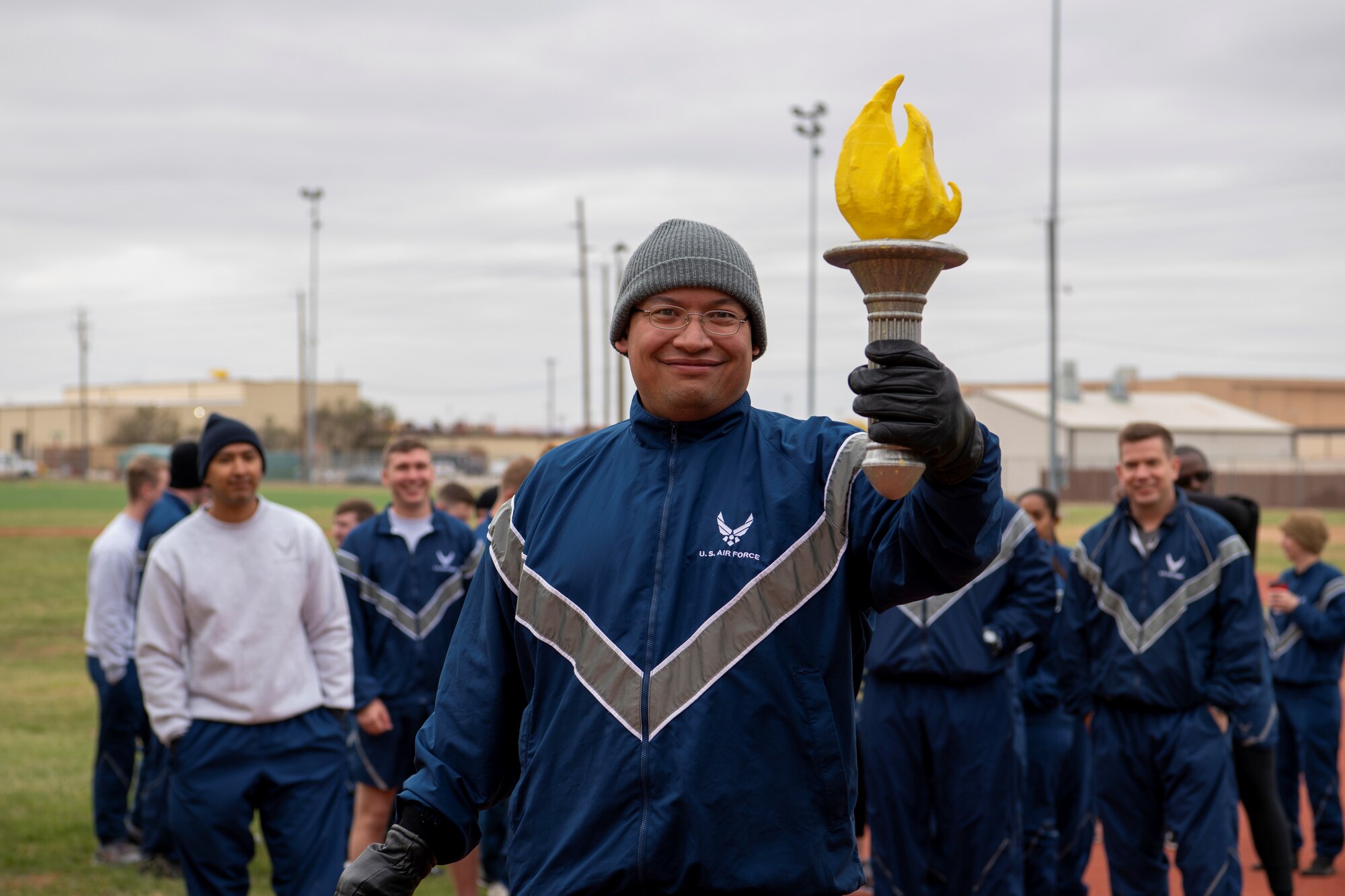 Tech. Sgt. James Reyes, 7th Operations Support Squadron aircrew flight equipment quality assurance NCO in charge, holds the torch for the sports day run at Dyess Air Force Base, Texas, Nov. 18, 2022. Dyess Airmen came together for sports day to show their unique strengths in diverse competitions while practicing teamwork and physical fitness. Competitions included a torch run, swimming, strong man challenge, volleyball, flag football, tug of war and a vehicle pull, with flash challenges throughout the day. (U.S. Air Force photo by Senior Airman Mercedes Porter)