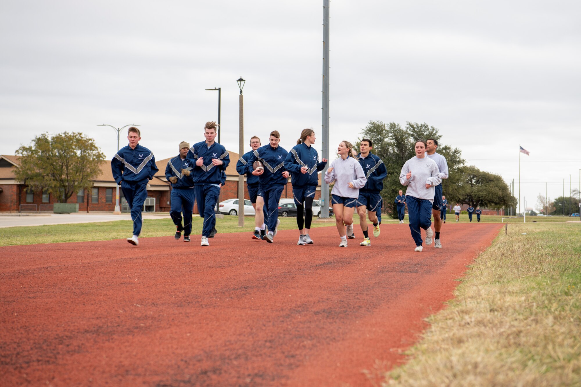 Dyess Airmen run 400-meter track during sports day at Dyess Air Force Base, Texas, Nov. 18, 2022. Dyess Airmen came together for sports day to show their unique strengths in diverse competitions while practicing teamwork and physical fitness. Competitions included a torch run, swimming, strong man challenge, volleyball, flag football, tug of war and a vehicle pull, with flash challenges throughout the day. (U.S. Air Force photo by Senior Airman Mercedes Porter)