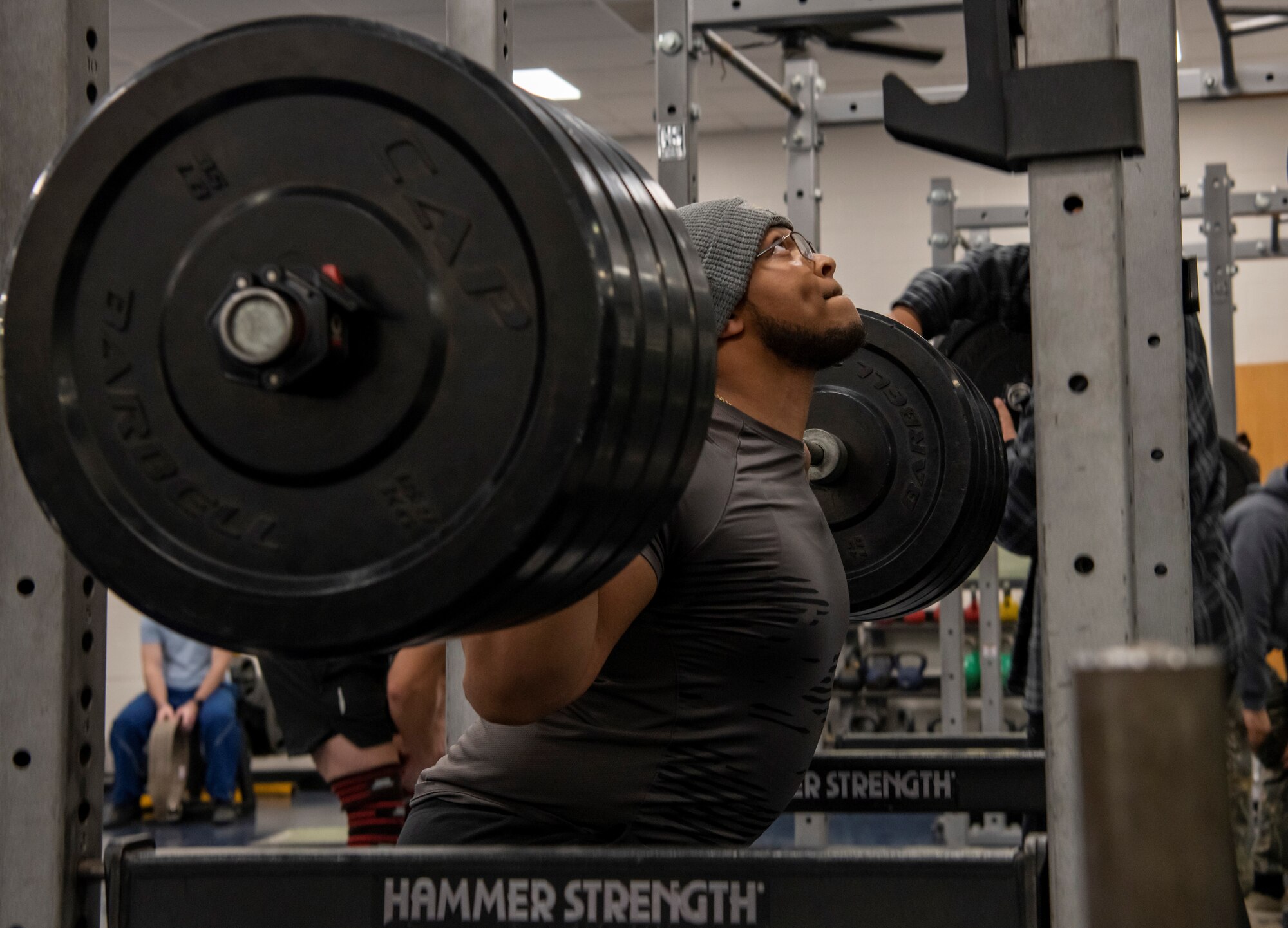 Senior Airman Devin Johnson, 7th Equipment Maintenance Squadron metals technician, squats with weights during sports day at Dyess Air Force Base, Texas, Nov. 18, 2022. Dyess Airmen came together for sports day to show their unique strengths in diverse competitions while practicing teamwork and physical fitness. Competitions included a torch run, swimming, strong man challenge, volleyball, flag football, tug of war and a vehicle pull, with flash challenges throughout the day. (U.S. Air Force photo by Senior Airman Mercedes Porter)