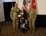 two men wearing u.s. army uniforms stand with a woman holding awards for a photo.