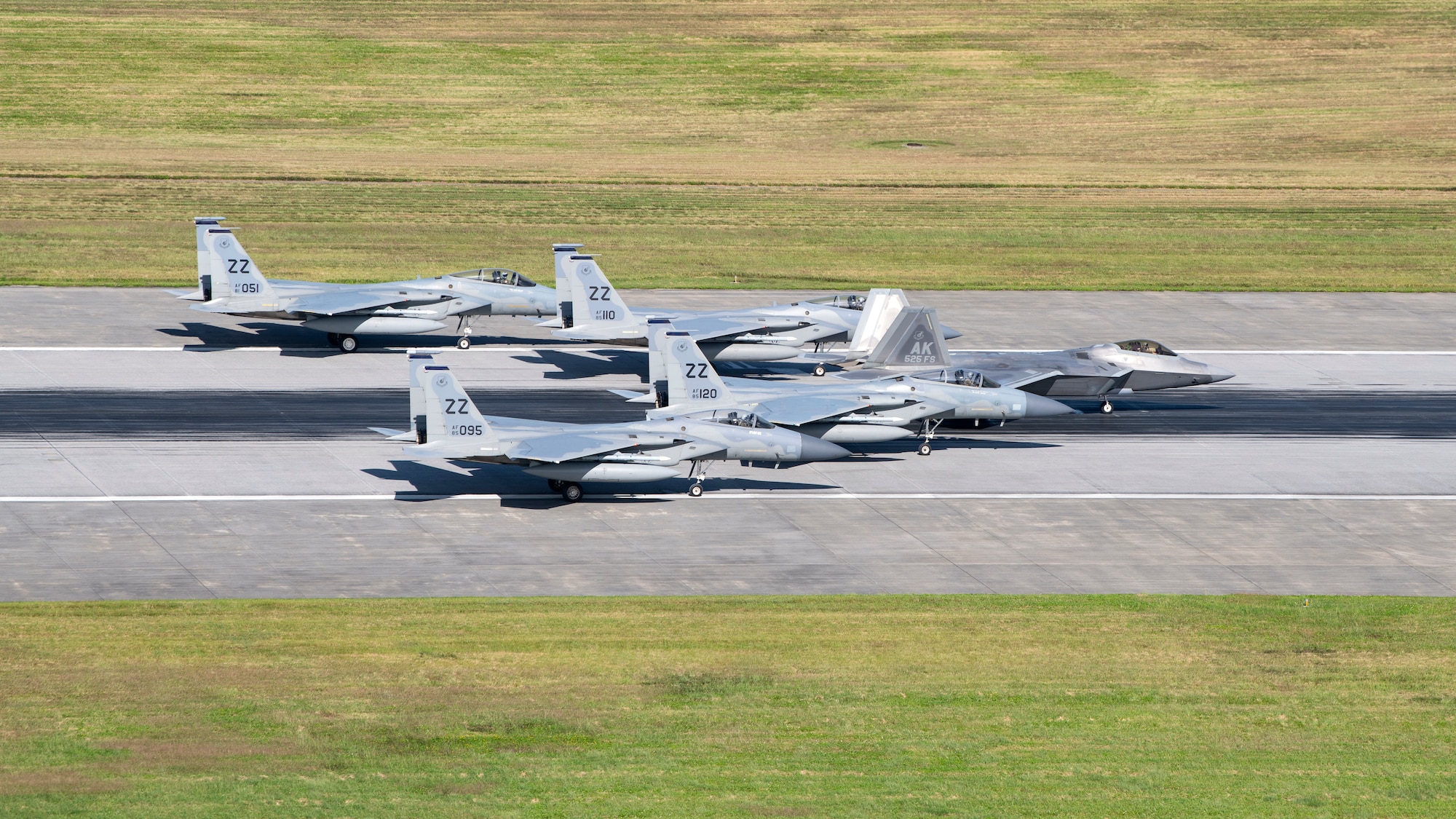 A formation of 44th Fighter Squadron F-15C Eagles and a 525th FS F-22A Raptor are stopped on the runway as part of a capabilities demonstration at Kadena Air Base, Japan, Nov. 22, 2022. Kadena’s ability to rapidly generate U.S. airpower is a vital function of its mission to ensure the stability and security of the Indo-Pacific region. (U.S. Air Force photo by Senior Airman Jessi Roth)
