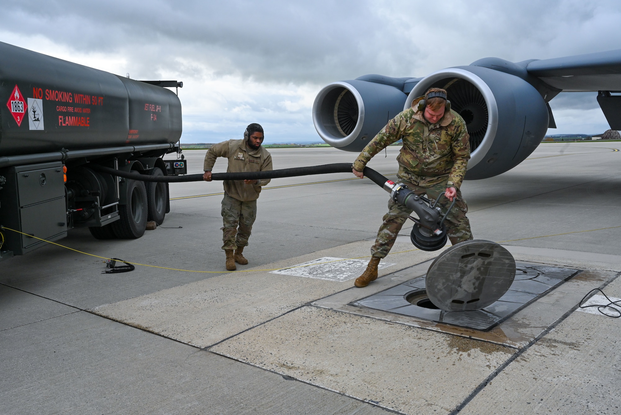 Two Airmen carry a hose.