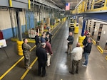 Members from NPS watch as DDJC employee Guillermo Urrea processes a package during a warehouse tour.
