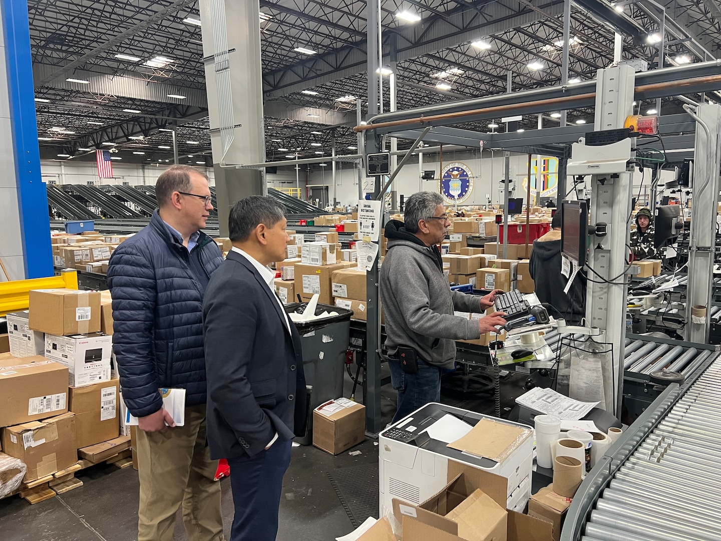 Members from NPS watch as DDJC employee Guillermo Urrea processes a package during a warehouse tour.