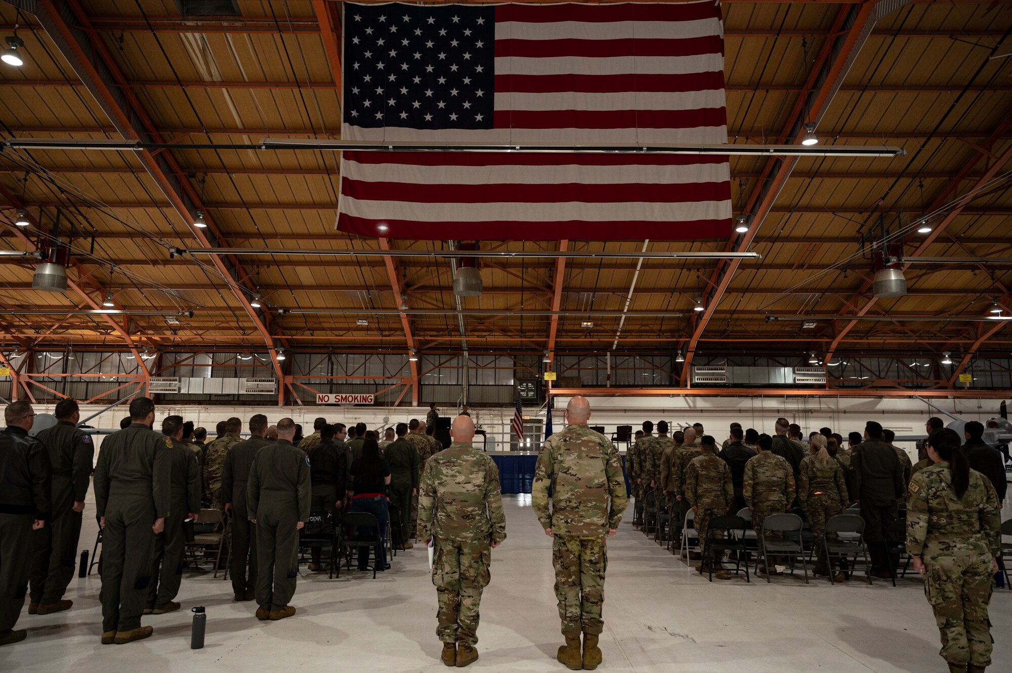 Airmen from the 49th Aircraft Maintenance Squadron stand for the pledge of allegiance during the 2022 Dedicated Crew Chief Appointment Ceremony at Holloman Air Force Base, New Mexico, Nov. 18, 2022. To become a DDC, a crew chief must have proficient technical knowledge of the MQ-9 Reaper to contribute to building combat-capable aircraft. (U.S. Air Force photo by Airman 1st Class Isaiah Pedrazzini)