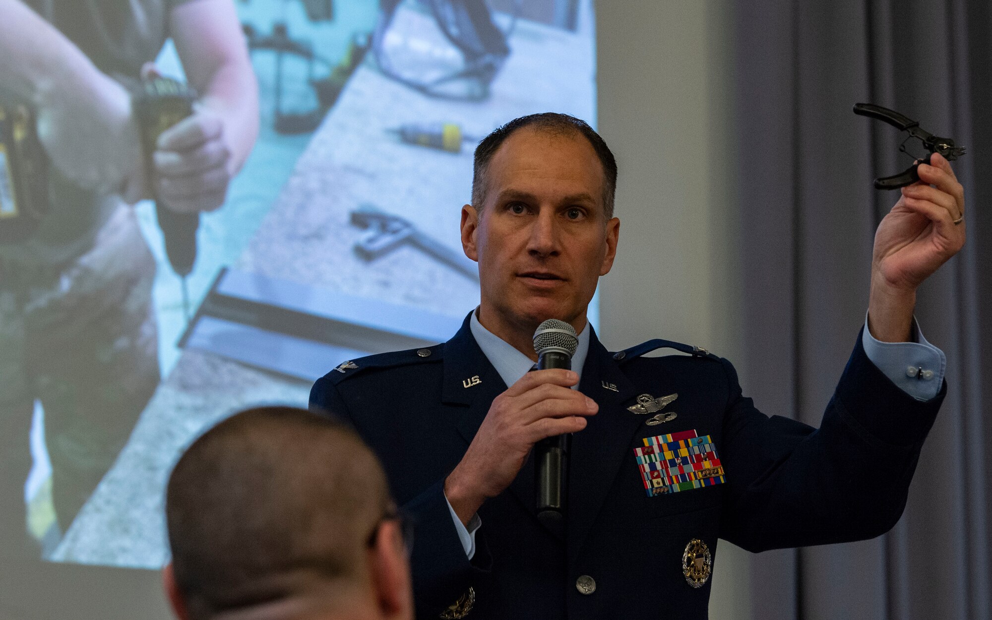 Col. Matt Husemann, 436th Airlift Wing commander, holds up a pair of pliers during the 2022 State of the Base briefing at The Landings on Dover Air Force Base, Delaware, Nov. 21, 2022. The pliers were fabricated at the Bedrock Innovation Lab by Team Dover Airmen. (U.S. Air Force photo by Roland Balik)