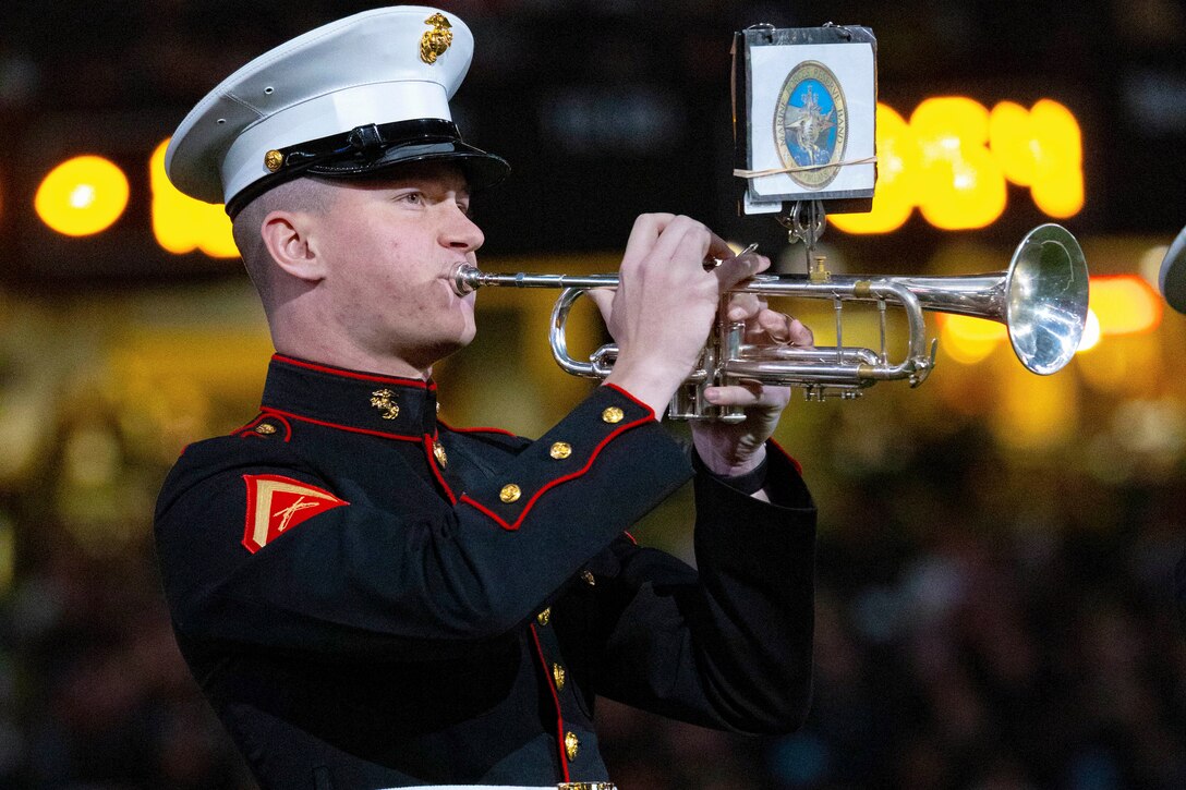 A Marine plays the trumpet with lights in the background.