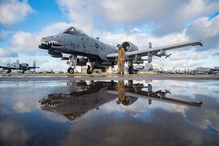 Airman stands beside plane