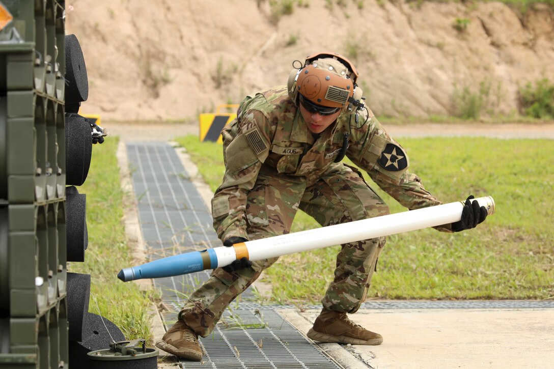 Soldier assigned to 5-17 Air Cavalry Squadron, 2nd Combat Aviation Brigade, 2nd Infantry Division, removes a Hydra 70 missile from an ammo crate to laod into the AH-64E Apache Helicopter,  July 19, 2022, Rodriguez Live Fire Complex, Republic of Korea. Pilots of the AH-64E are required to qualify on all of the Apaches weapon systems. (U.S. Army photo by Sgt. Oscar Toscano)