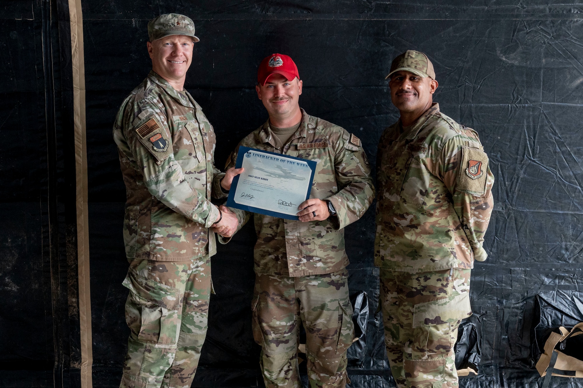 U.S. Air Force Staff Sgt. Sean Kirby, an emergency management contingency skills instructor assigned to the 554th Rapid Engineer Deployable Heavy Operational Repair Squadron Engineers Squadron, receives the Linebacker of the Week Award from U.S. Air Force Brig. Gen Paul Birch, the 36th Wing commander, and Chief Master Sgt. Jose Ramon, the senior enlisted leader of the 36th Maintenance Group, at Andersen Air Force Base, Guam, Nov. 16, 2022. The Team Andersen Linebacker of the Week recognizes outstanding enlisted, officer, civilian and total force personnel who have had an impact on achieving Team Andersen’s mission, vision and priorities. (U.S. Air Force photo by Airman 1st Class Emily Saxton)