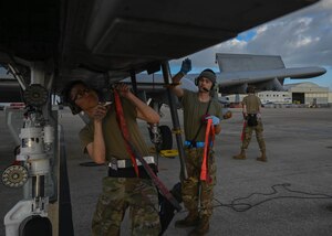 A photo of two men in military uniforms working on a plane.
