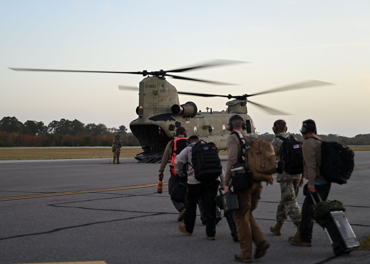 A photo of a group of people in military uniforms walking towards a helicopter.