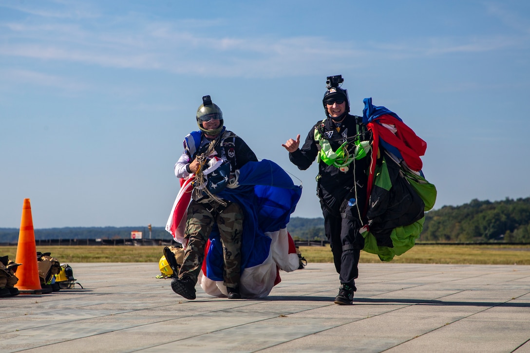 From left, U.S. Marine Corps 1st Sgt. Michael A. Flor, the first sergeant of Marine Corps Air Facility Quantico, and Bobby Page, a skydiver, arrive at the Aircraft Rescue and Fire Fighter Rodeo at MCAF on Marine Corps Base Quantico, Sep. 2, 2022. The ARFF Rodeo is a competition for Marines to showcase their operational knowledge of firefighting tactics, techniques, and procedures.(U.S. Marine Corps Photo by Lance Cpl. George Nudo)