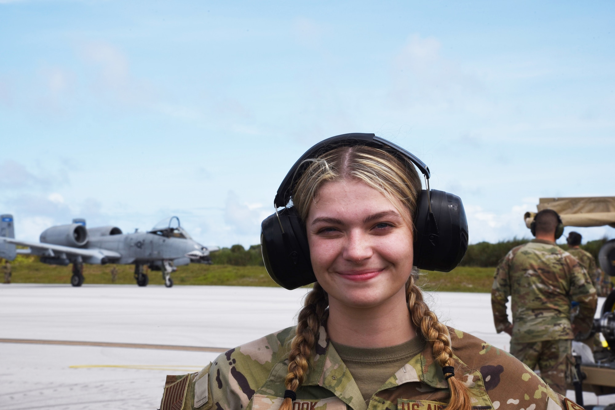 Photo of an Airman on a flight line with aircraft in the background