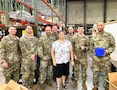 group of u s army soldiers pose for photos with woman.