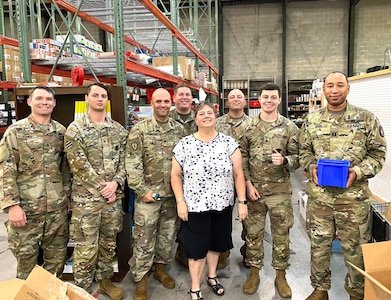 group of u s army soldiers pose for photos with woman.