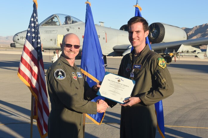 U.S. Air Force Major Kyle Adkison, A-10 Pilot assigned to the 53rd Wing is presented the Distinguished Flying Cross with Combat Service by U.S. Air Force Major General R. Scott Jobe, Director of Plans, Programs, and Requirements, Headquarters Air Combat Command, during a ceremony at Nellis Air Force Base, Nevada, Nov. 22, 2022. The distinguished flying cross is awarded for heroism or extraordinary achievement while participating in aerial flight. Both heroism and achievement must be entirely distinctive, involving operations that are not routine.