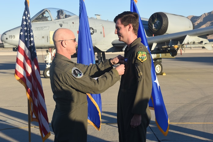 U.S. Air Force Major Kyle Adkison, A-10 Pilot assigned to the 53rd Wing is presented the Distinguished Flying Cross with Combat Device by U.S. Air Force Major General R. Scott Jobe, Director of Plans, Programs, and Requirements, Headquarters Air Combat Command, during a ceremony at Nellis Air Force Base, Nevada, Nov. 22, 2022. The "C" device was established in 2016 to distinguish an award earned for exceptionally meritorious service or achievement performed under combat conditions.