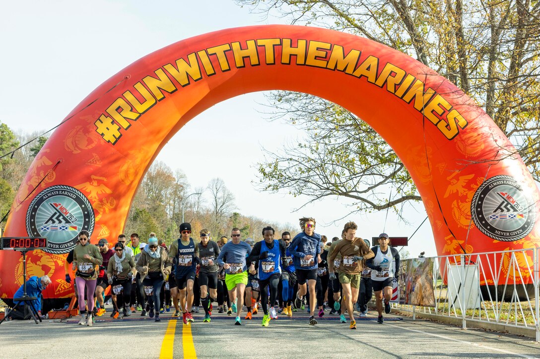 People run under an inflatable race arch.