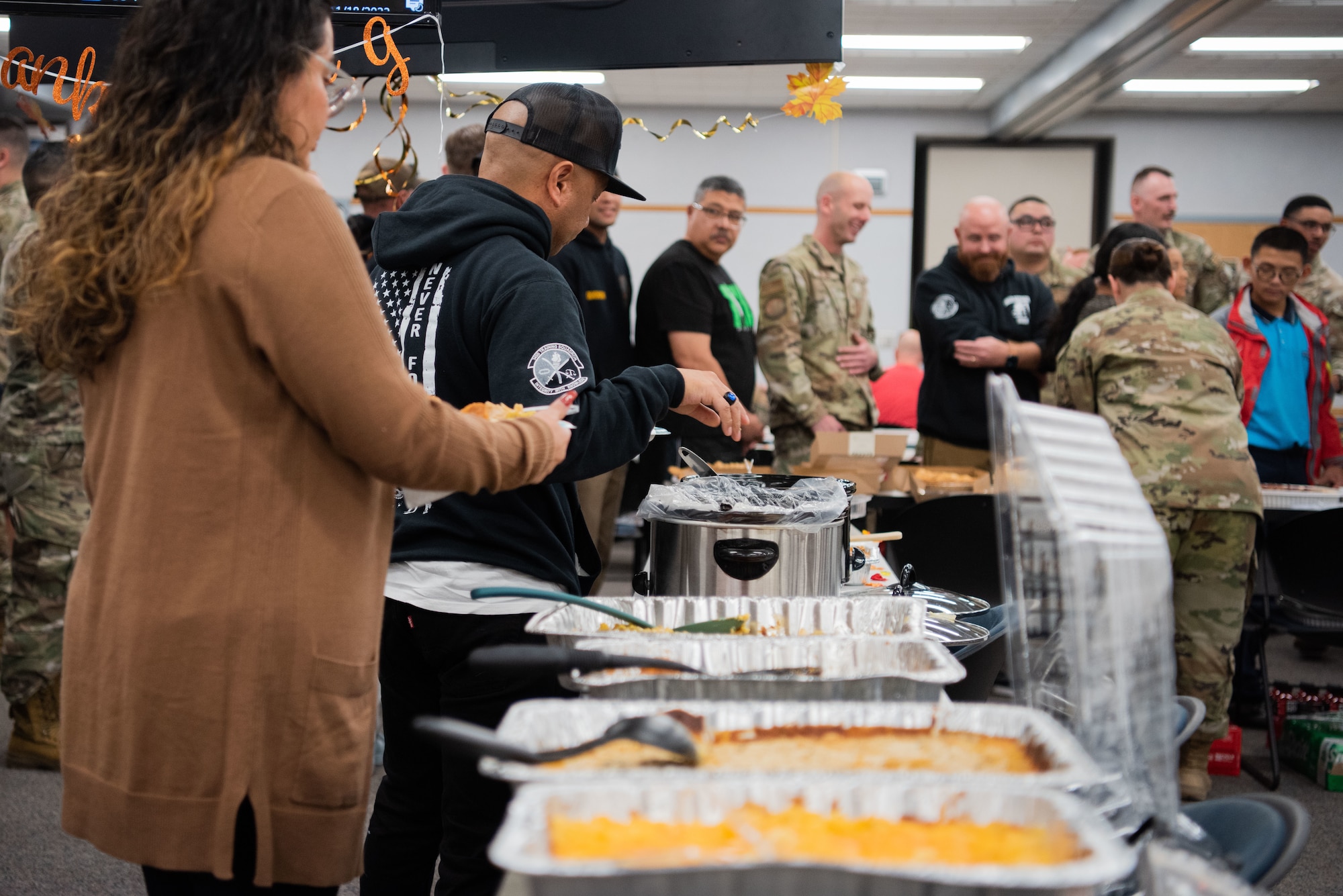 Man puts food on his plate, while others are around him are doing the same.