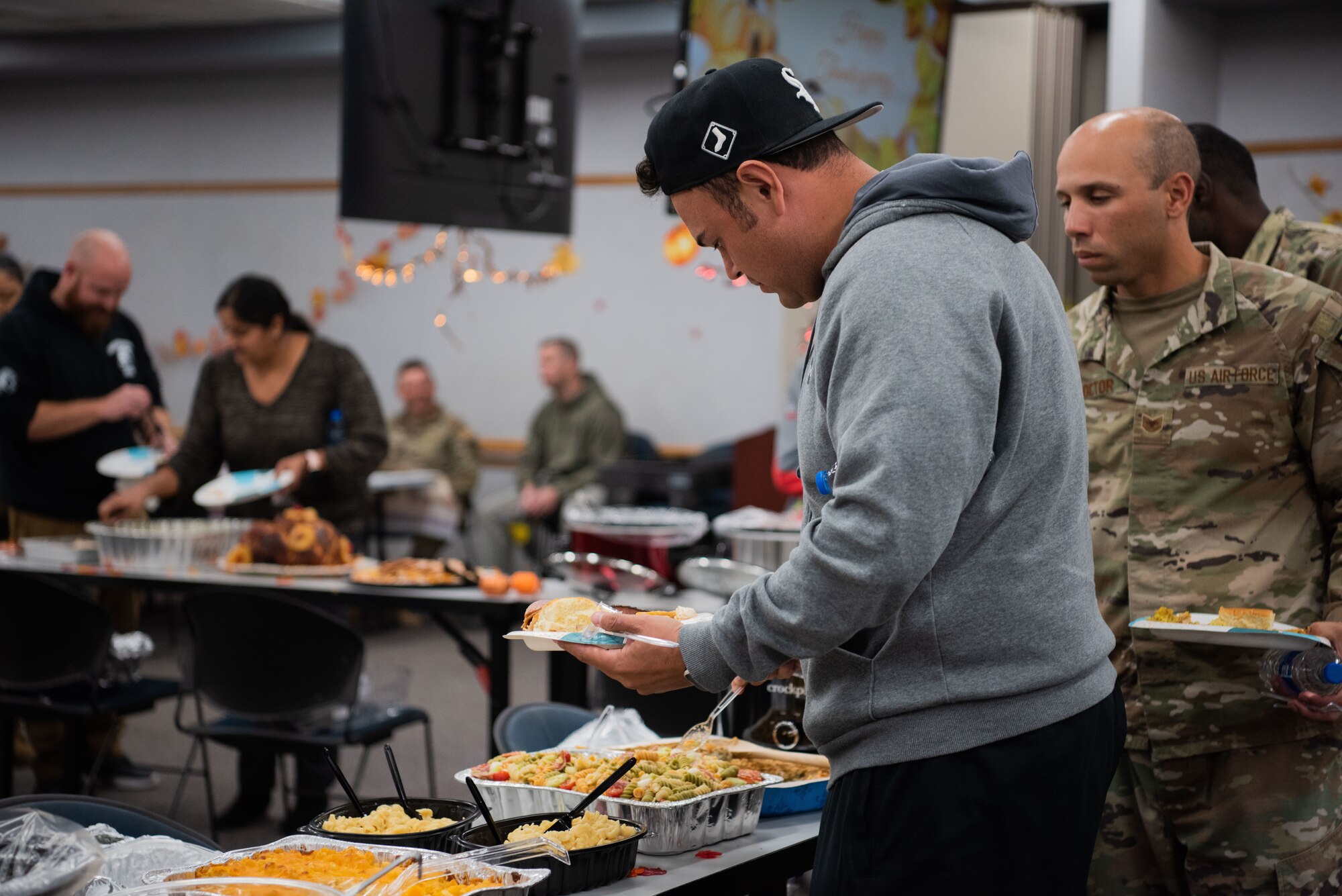 Man puts food on his plate, while others are around him are doing the same.