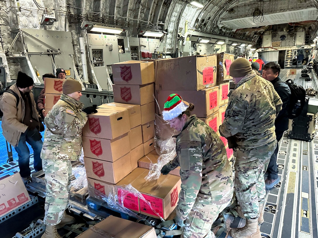 Soldiers in uniform unload boxes from an aircraft.