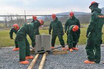 Service members from the Pennsylvania National Guard's 3rd CBRN (Chemical, Biological, Radiological, and Nuclear) Task Force move a block of concrete using crowbars and pipes during a Homeland Response Force collective training exercise Nov. 18, 2022, at Fort Indiantown Gap, Pa.