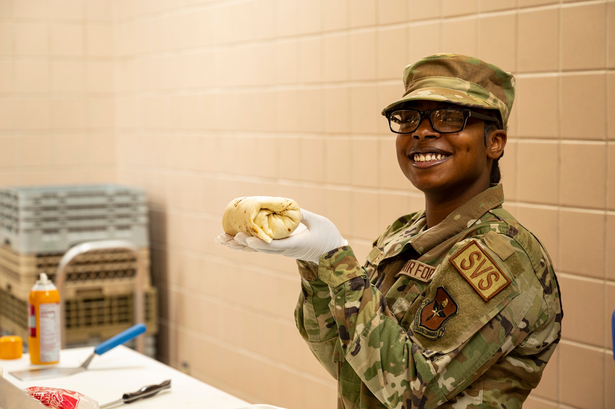 U.S. Air Force Airman 1st Class Sapphire Batts, 49th Force Support Squadron services apprentice, poses after making a lunch wrap for an Airman at the Shifting Sands Dining Facility at Holloman Air Force Base, New Mexico, Nov. 18, 2022. The Shifting Sands mission is to provide the highest quality food, service and standards of excellence in support of an Airman's readiness in their mission. (U.S. Air Force photo by Airman 1st Class Isaiah Pedrazzini)