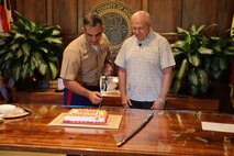 U.S. Marine Corps Col Speros Koumparakis, commanding officer, Marine Corps Base Hawaii, meets with Mayor Rick Blangiardi, mayor of Honolulu, to cut a birthday cake at City Hall in Honolulu, Hawaii, Nov. 16, 2022. The purpose of the visit was to share the tradition of cutting a cake in honor of the 247th birthday of the Marine Corps with the Mayor and city officials of Honolulu. (U.S. Marine Corps photo by Chief Warrant Officer 2 William Faffler)