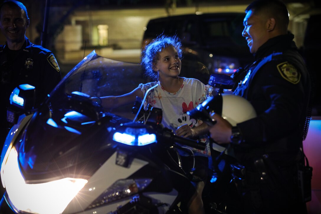 A Police Officer with the Honolulu Police Department showcases his patrol motorcycle to a child during a National Night Out event, Marine Corps Base Hawaii, Nov. 16, 2022. The event is an annual community-building campaign that promotes police-community partnerships and neighborhood camaraderie to enhance the relationship between neighbors and law enforcement while bringing back a true sense of community. (U.S. Marine Corps Photo by Gunnery Sgt. Orlando Perez)
