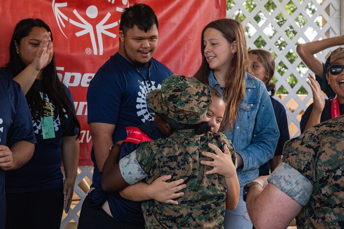 A Special Olympics athlete hugs U.S. Marine Corps Staff Sgt. Gracia Kayinamura, admin chief, Marine Corps Base Hawaii, after being awarded during the Special Olympics Hawaii 2022 Holiday Classic event aboard MCBH, Nov. 19-20, 2022. Special Olympics Hawaii is an organization that provides year-round sports training and competition for children and adults with intellectual disabilities. The Holiday Class is an annual event hosted by MCBH to foster relations between the local and military communities. (U.S. Marine Corps photo by Cpl. Israel Ballaro).