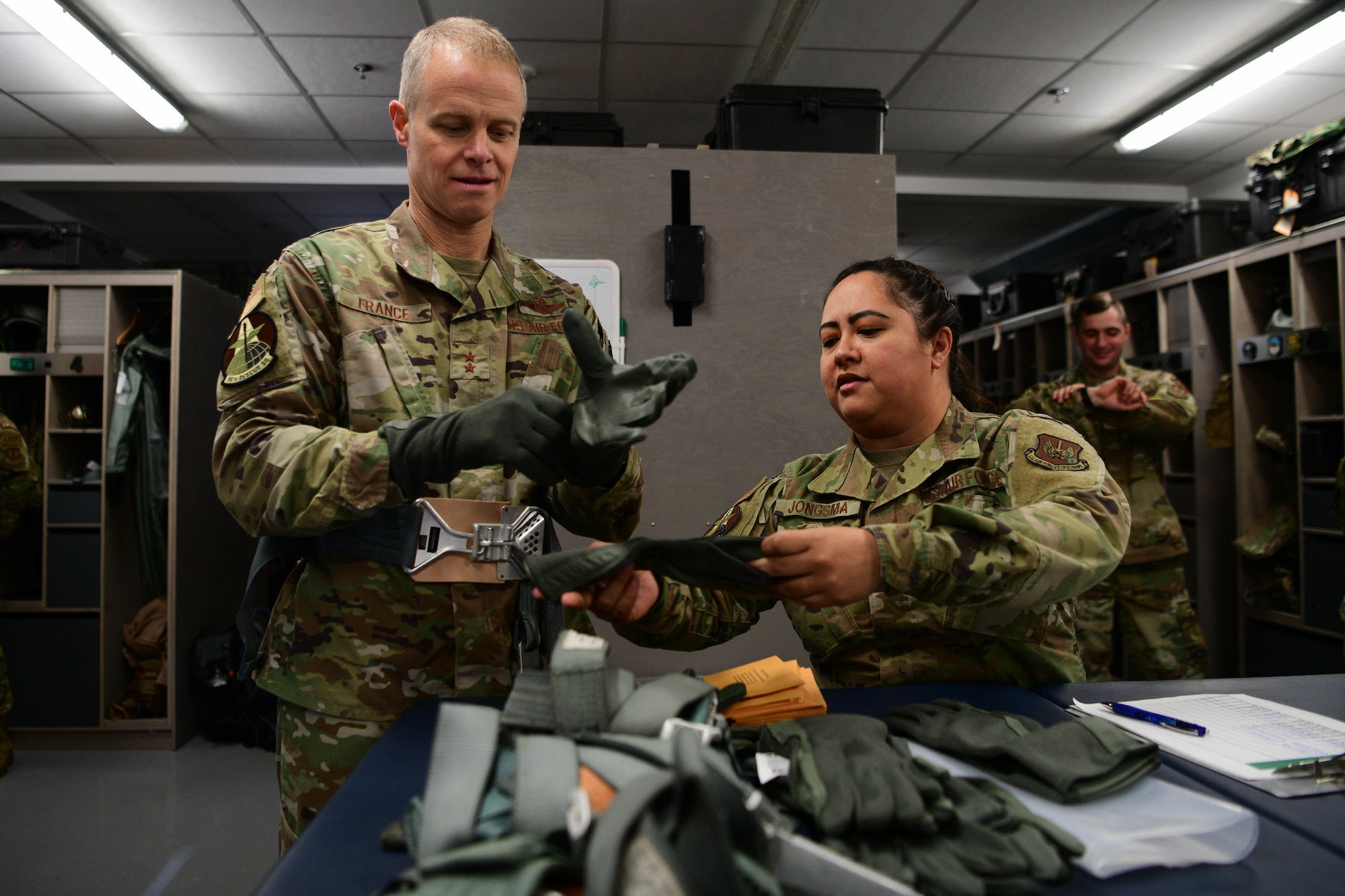 U.S. Air Force Tech. Sgt. Anna Jongsma, 31st Operations Support Squadron main shop aircrew flight equipment NCOIC, right, gives flight gloves to U.S. Air Force Maj. Gen. Derek France, Third Air Force commander, before he flies in an HH-60G Pave Hawk assigned to the 56th Rescue Squadron at Aviano Air Base, Italy, Nov. 21, 2022. France is a command pilot with more than 2,900 hours in the F-15 Eagle, F-22 Raptor and F-16 Fighting Falcon. (U.S. Air Force photo by Senior Airman Brooke Moeder)
