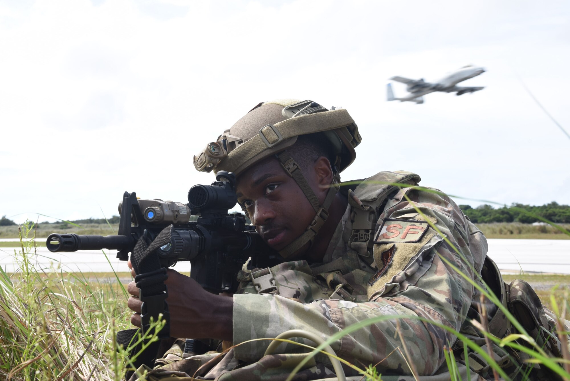 Photo of an Airman with a rifle laying prone in a field