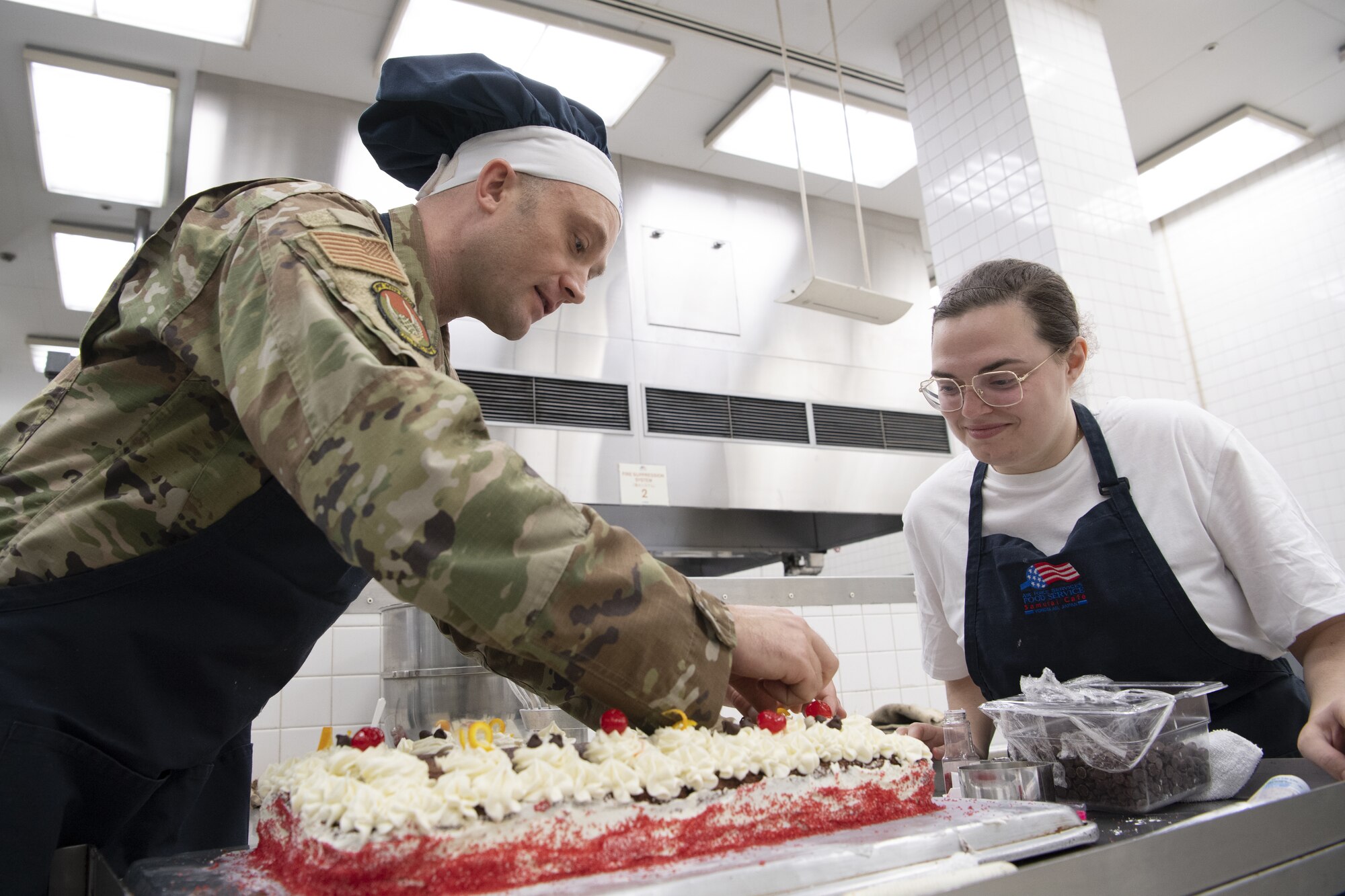 Lt. Col. Jordan Hayes, 374th Force Support Squadron commander, and Staff Sgt. Kylee Masters Thomas, 374th FSS food service shift leader, decorate a cake in preparation to serve Thanksgiving meals at the Samurai Café Dining Facility at Yokota Air Base, Japan, Nov. 24, 2022. U.S. Ambassador to Japan Rahm Emanuel, U.S. Air Force Lt. Gen. Ricky Rupp, Commander of U.S. Forces Japan and Fifth Air Force, and 374th Airlift Wing leadership took time to serve and celebrate Thanksgiving Day alongside service members and families assigned to Yokota. (U.S. Air Force photo by Tech. Sgt. Christopher Hubenthal)