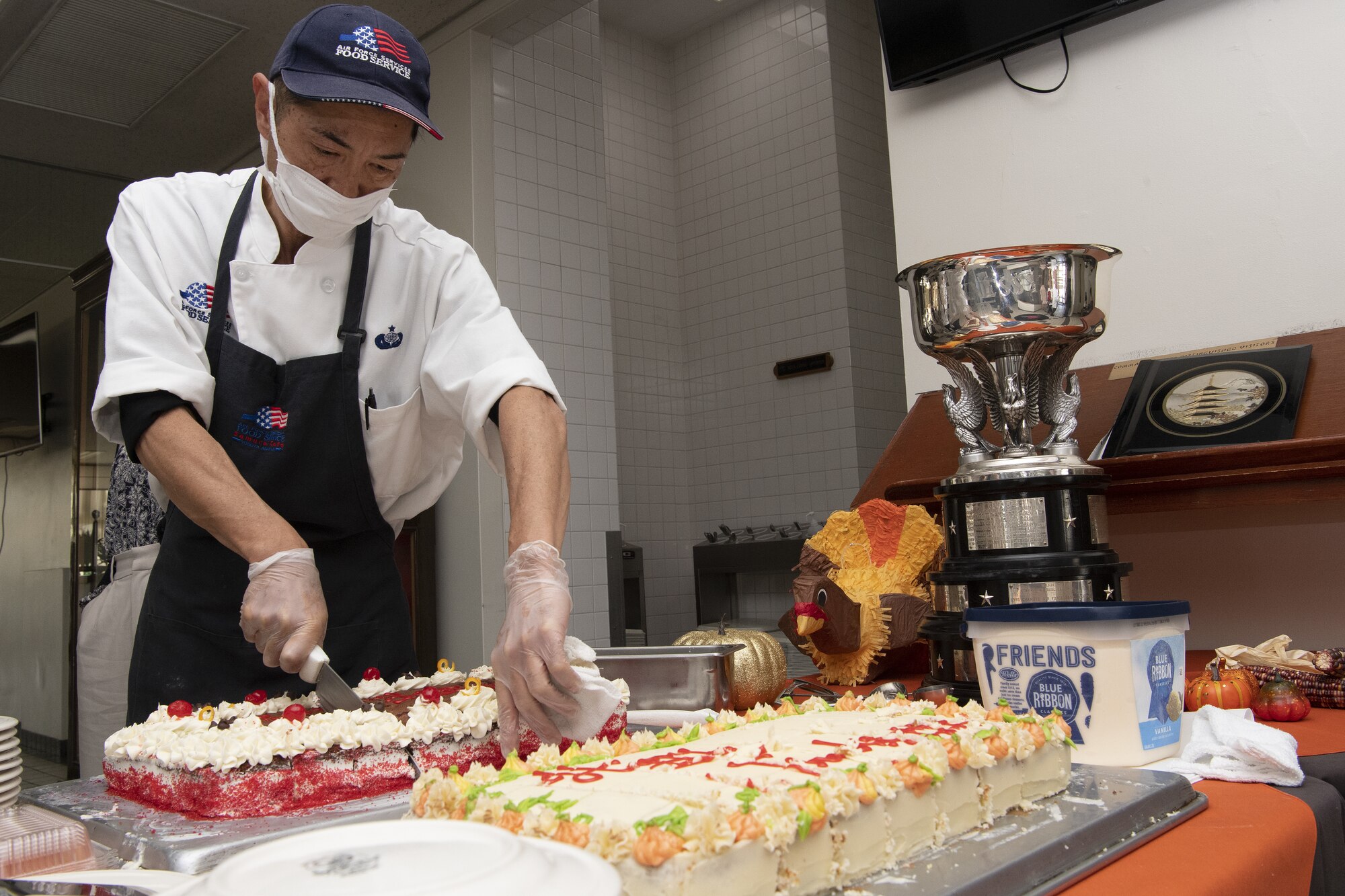 Tomohiro Ishibishi, 374th Force Support Squadron Samurai Café cook, cuts cake to serve as part of Thanksgiving meals at the Samurai Café Dining Facility at Yokota Air Base, Japan, Nov. 24, 2022. U.S. Ambassador to Japan Rahm Emanuel, U.S. Air Force Lt. Gen. Ricky Rupp, Commander of U.S. Forces Japan and Fifth Air Force, and 374th Airlift Wing leadership took time to serve and celebrate Thanksgiving Day alongside service members and families assigned to Yokota. (U.S. Air Force photo by Tech. Sgt. Christopher Hubenthal)