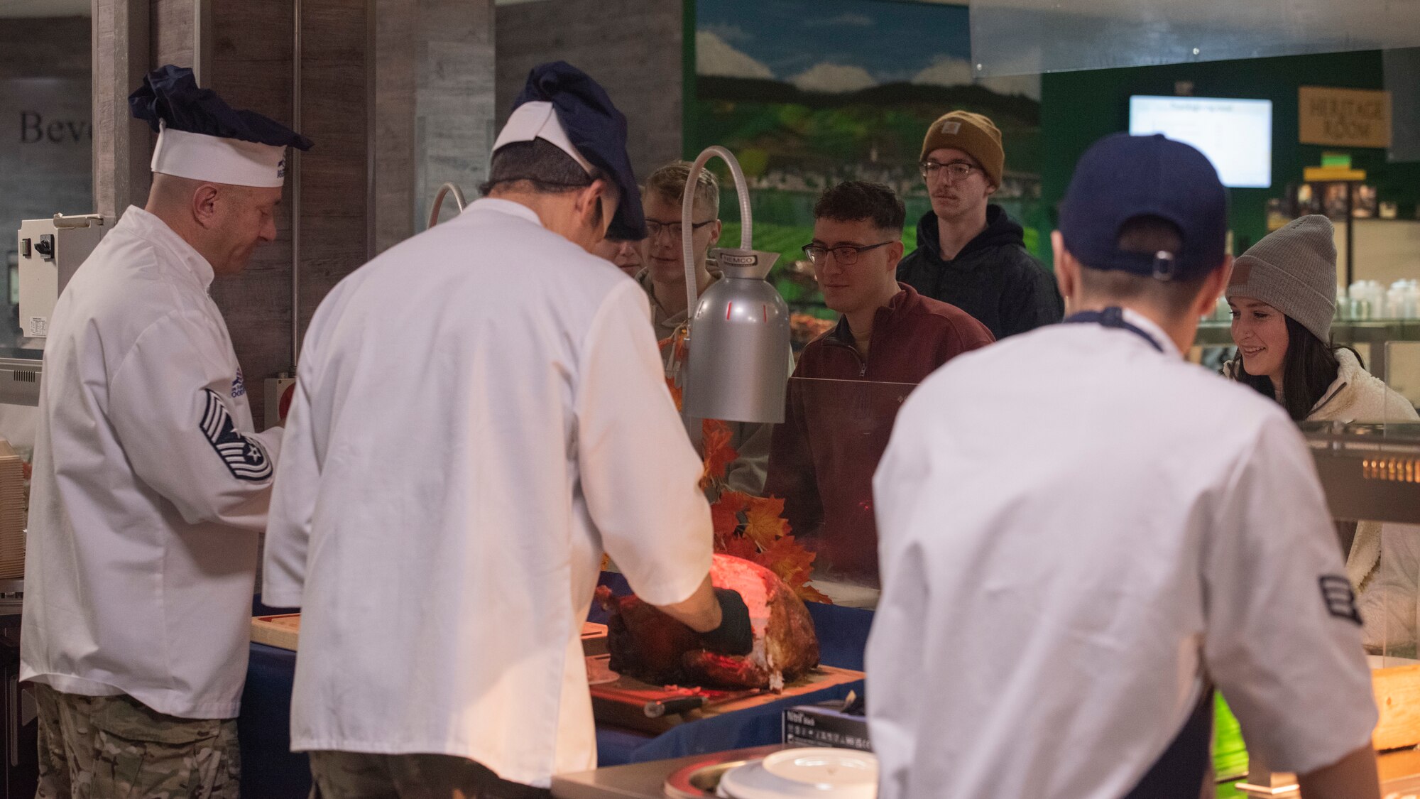 People serve others a holiday themed meal at a base dining facility.