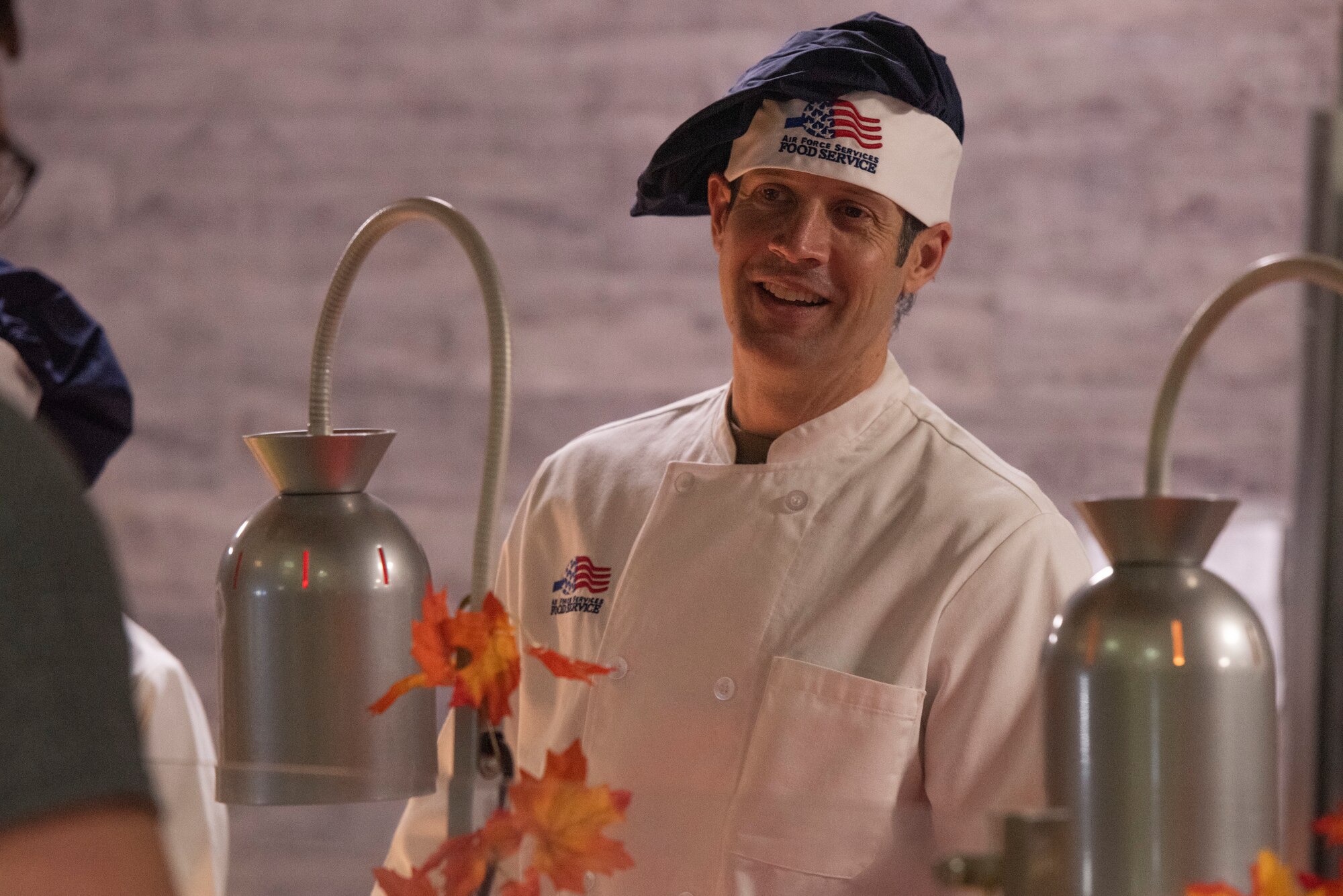 A man smiles while serving food