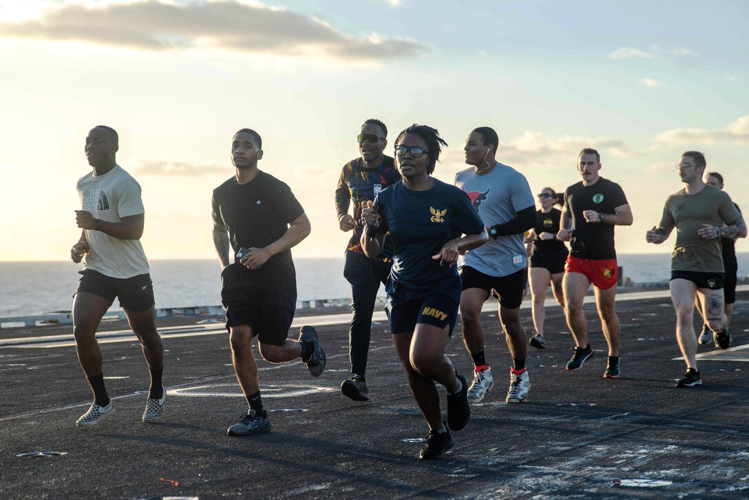 Sailors jog on the deck of a ship.