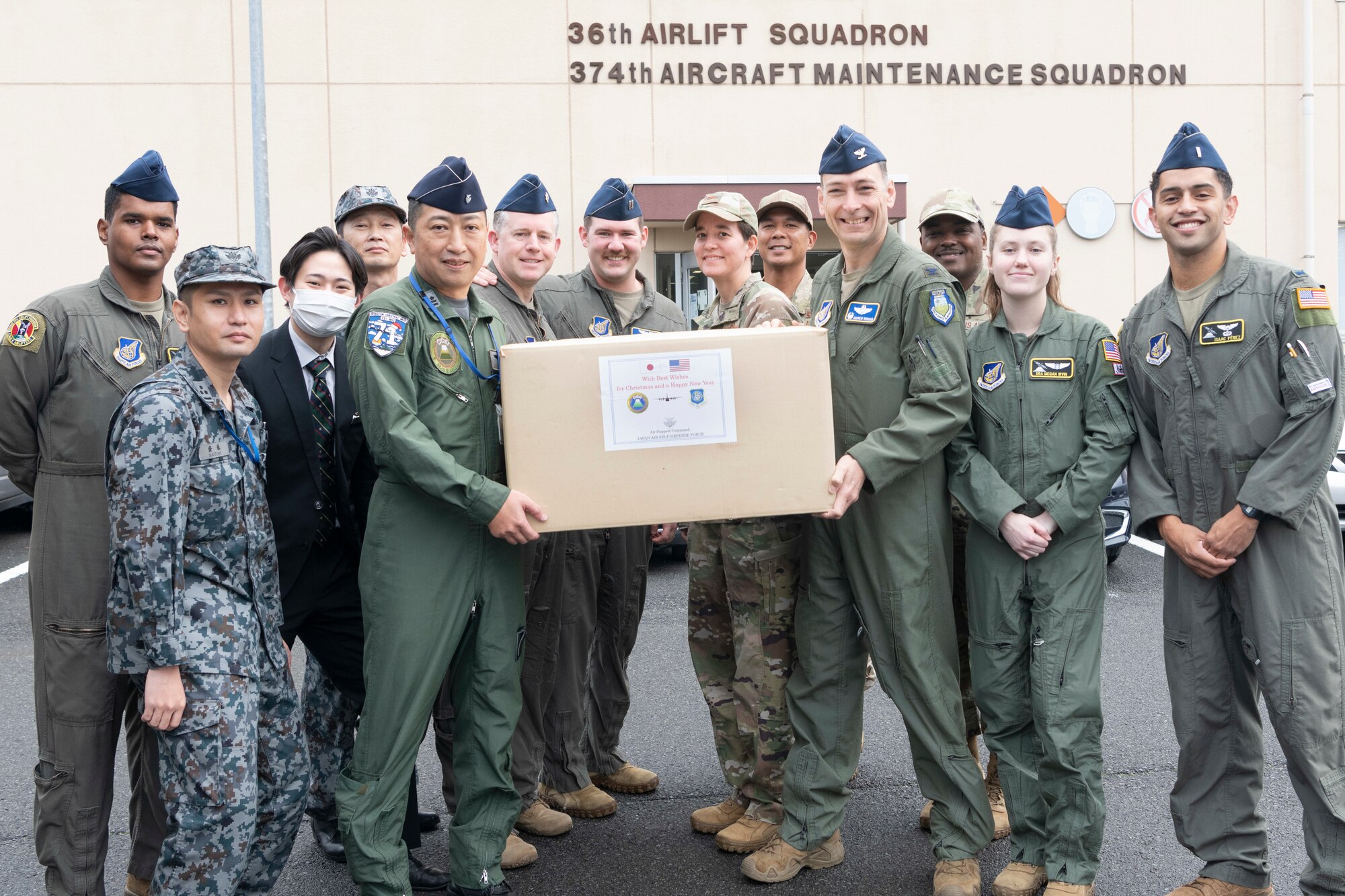 Leadership from the 374th Airlift Wing and Airmen from the 36th Airlift Squadron receive a donation of humanitarian supplies for Operation Christmas Drop from Japan Air Self-Defense Force members of Headquarters Air Support Command at Yokota Air Base, Japan, Nov. 21, 2022.