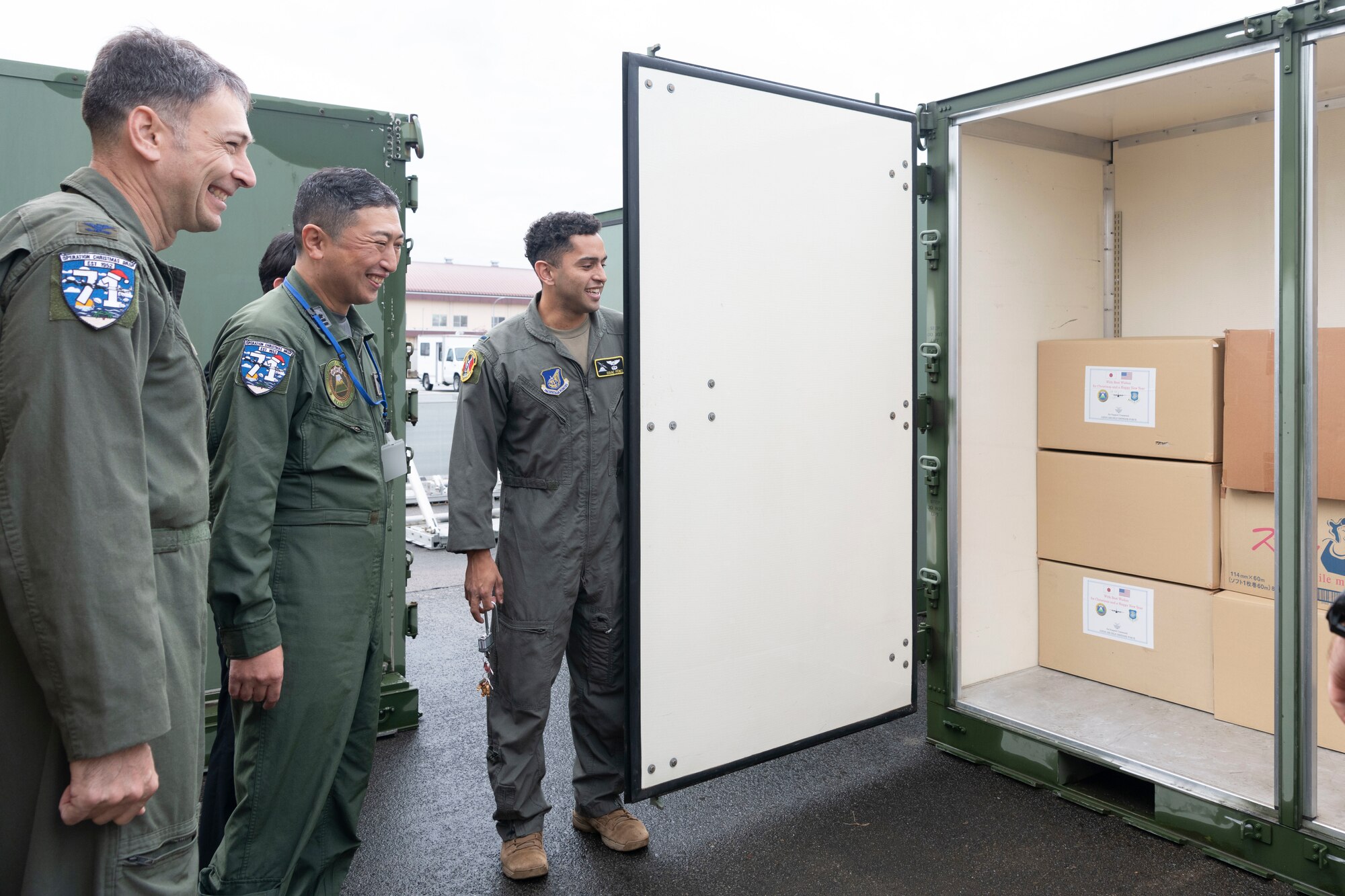First Lt. Isaac Perez, 36th Airlift Squadron C-130J pilot, shows Col. Andrew Roddan, 374th Airlift Wing commander and Japan Air Self-Defense Force Lt. Col. Takahiro Seki, Headquarters Air Support Command, A3/5 Directorate, A5 Division senior officer, where donations for Operation Christmas Drop are stored at Yokota Air Base, Japan, Nov. 21, 2022.