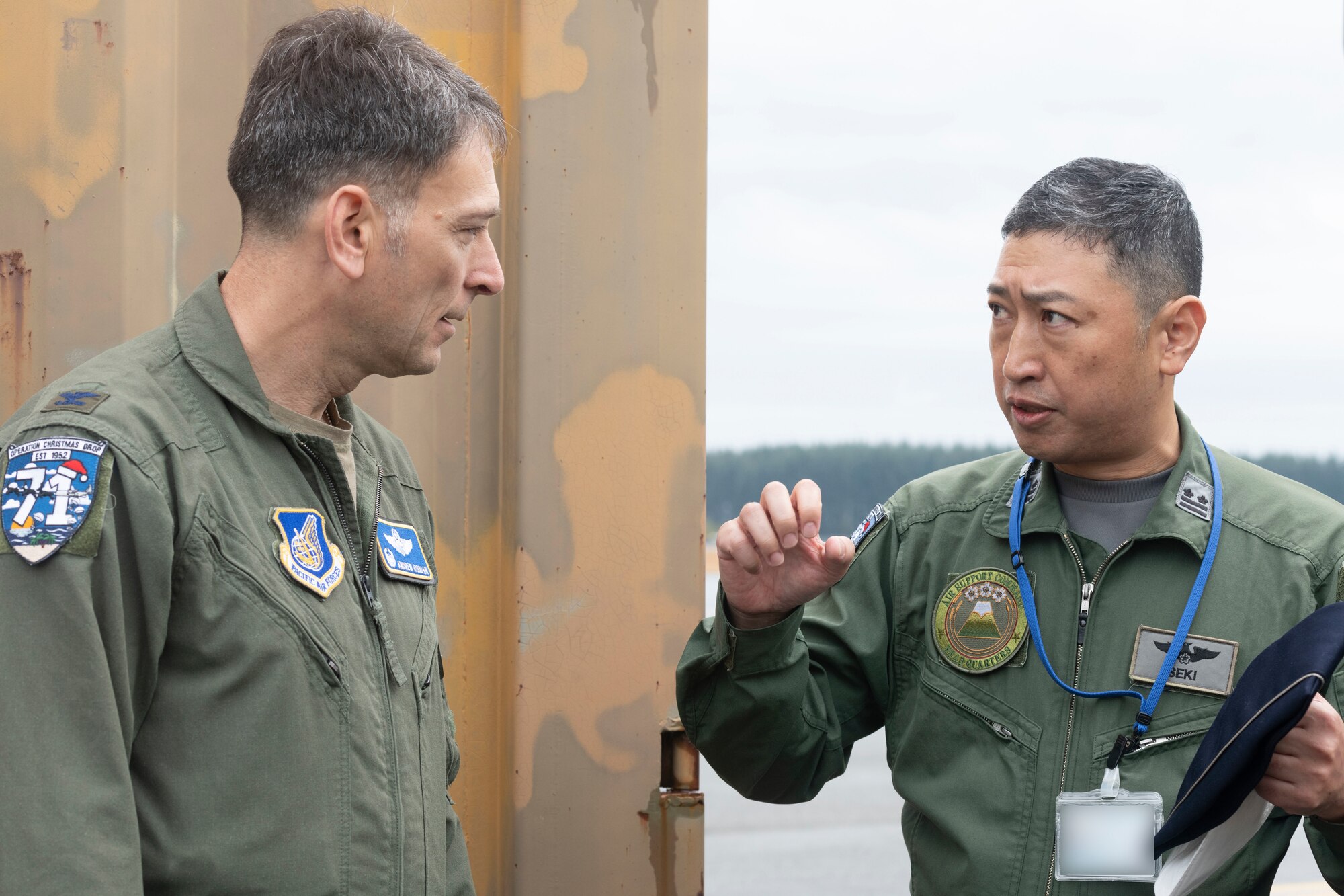 Japan Air Self-Defense Force Lt. Col. Takahiro Seki, Headquarters Air Support Command, A3/5 Directorate, A5 Division senior officer, speaks with Col. Andrew Roddan, 374th Airlift Wing commander, after receiving Operation Christmas Drop donations from JASDF at Yokota Air Base, Japan, Nov. 21, 2022.