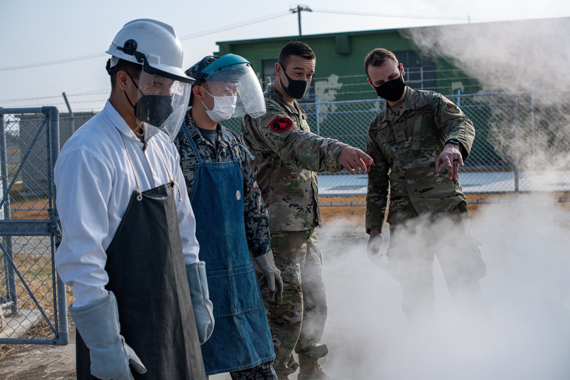 Airmen and a Japan military member fill a liquid oxygen tank.