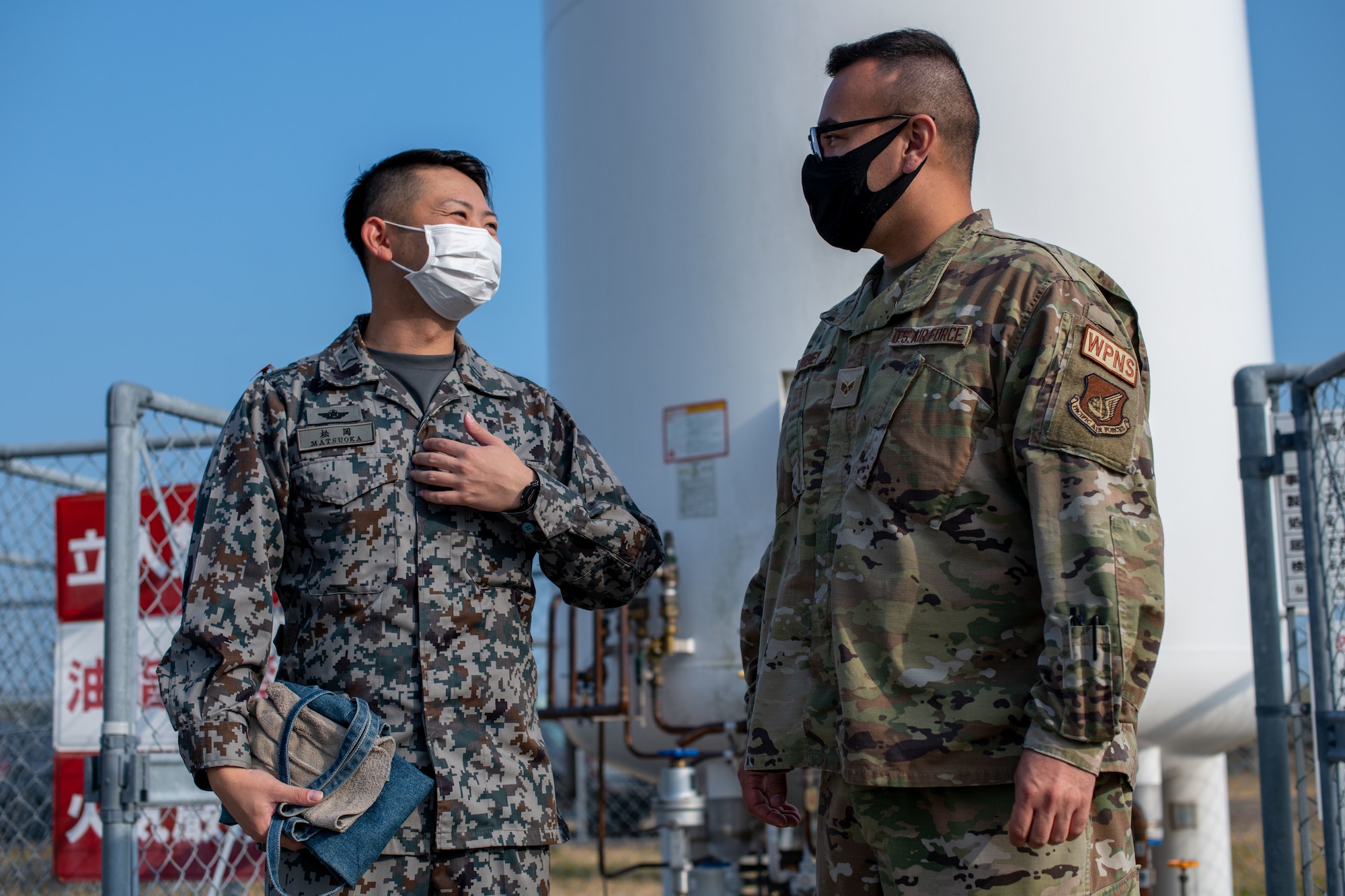 An Airman and Japan military member speak to each other.