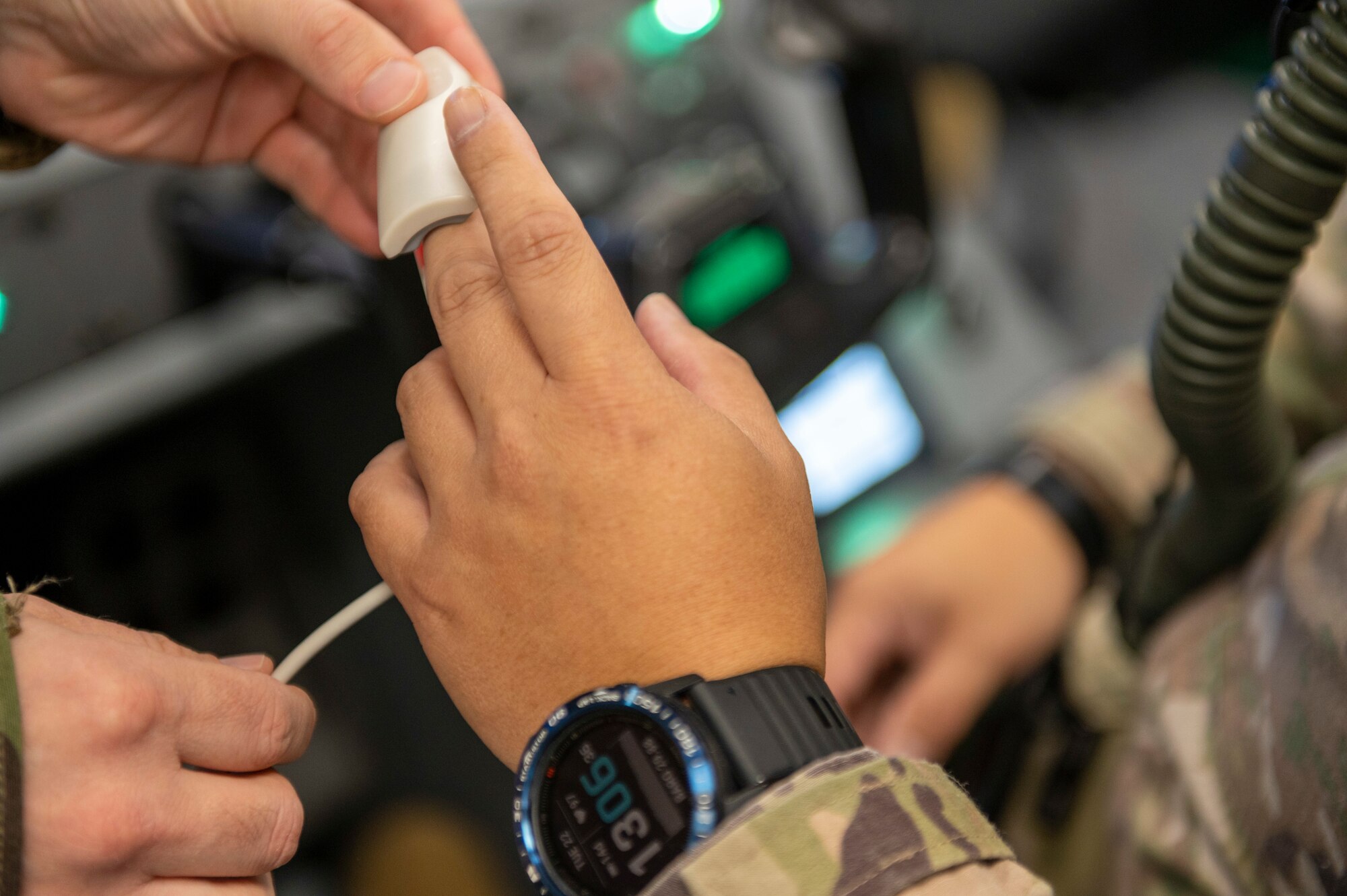Close up of hands, one pair attaches a device to the middle finger of another.