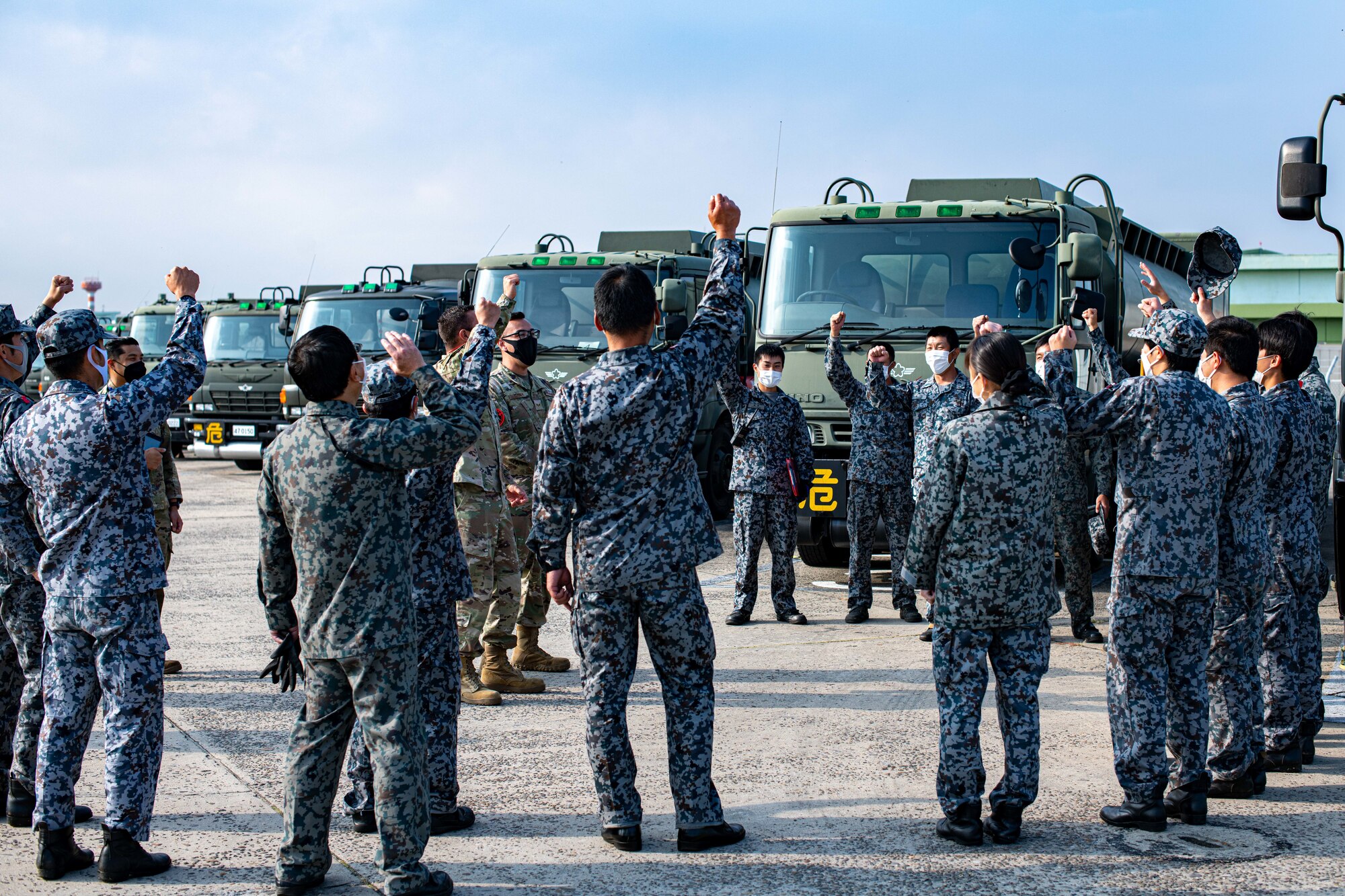 Airmen and Japanese military cheer.