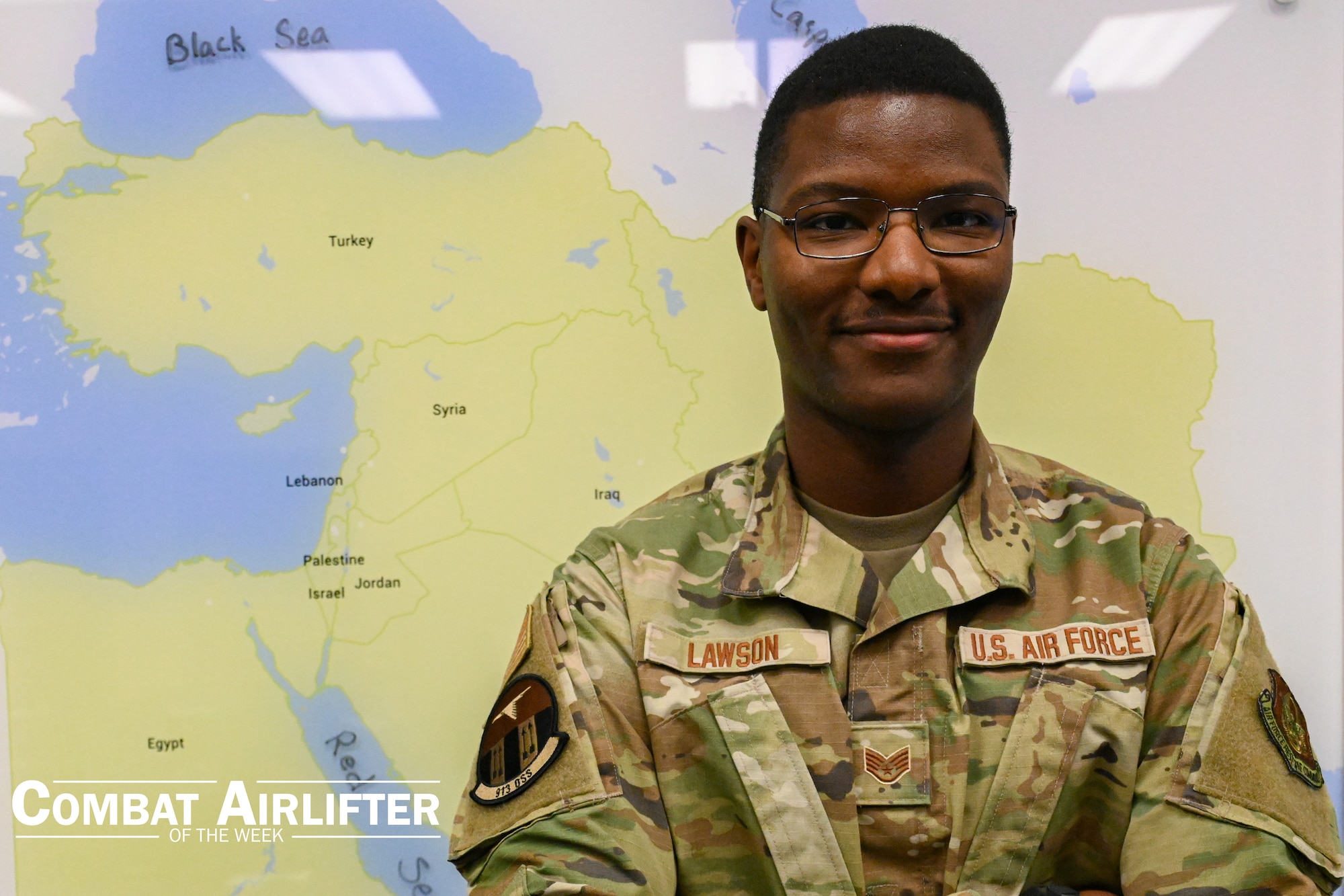 A man in uniform poses for a photo in front of a map