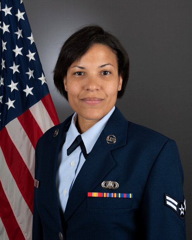An official headshot photo of A1C Beatrice Scorby in front of the American flag. She is wearing the blue service dress uniform.