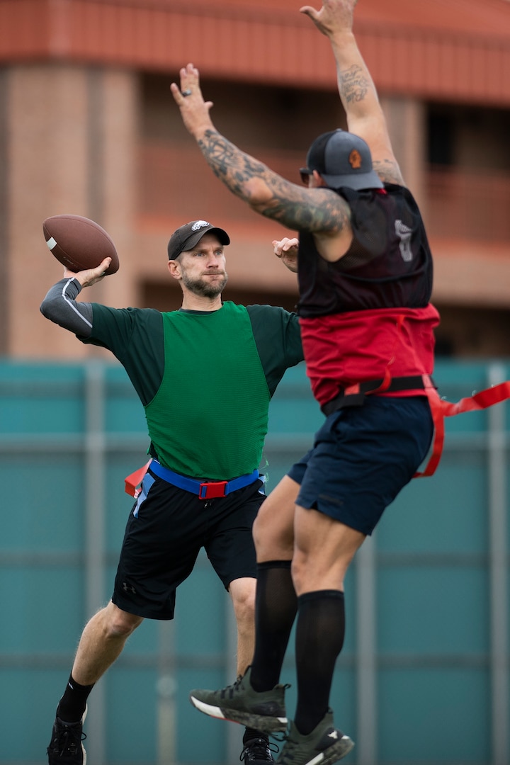 Man prepares to throw football while another man defends him